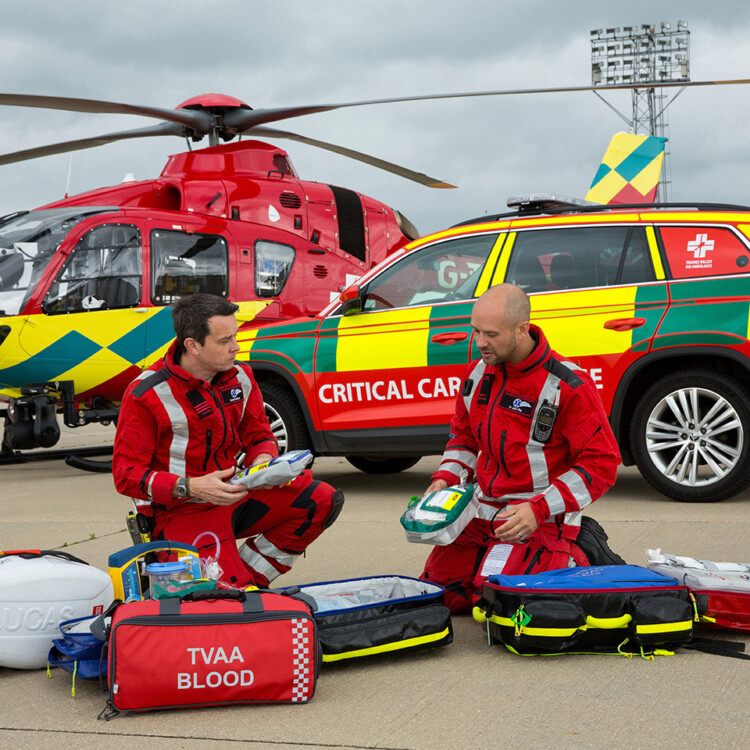 paramedics unpacking equipment infront of helicopter and car