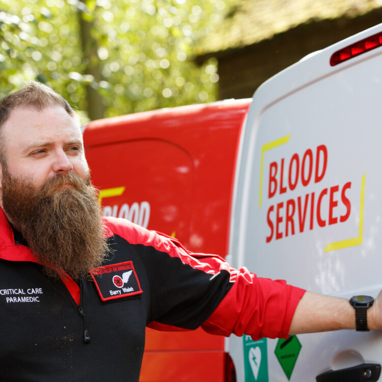 Critical Care Paramedic holds open door of blood delivery van