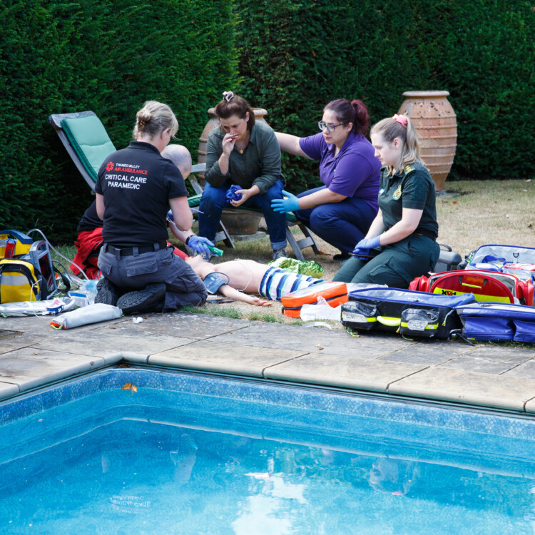 Training scenario featuring paramedics treating a patient at the side of a pool