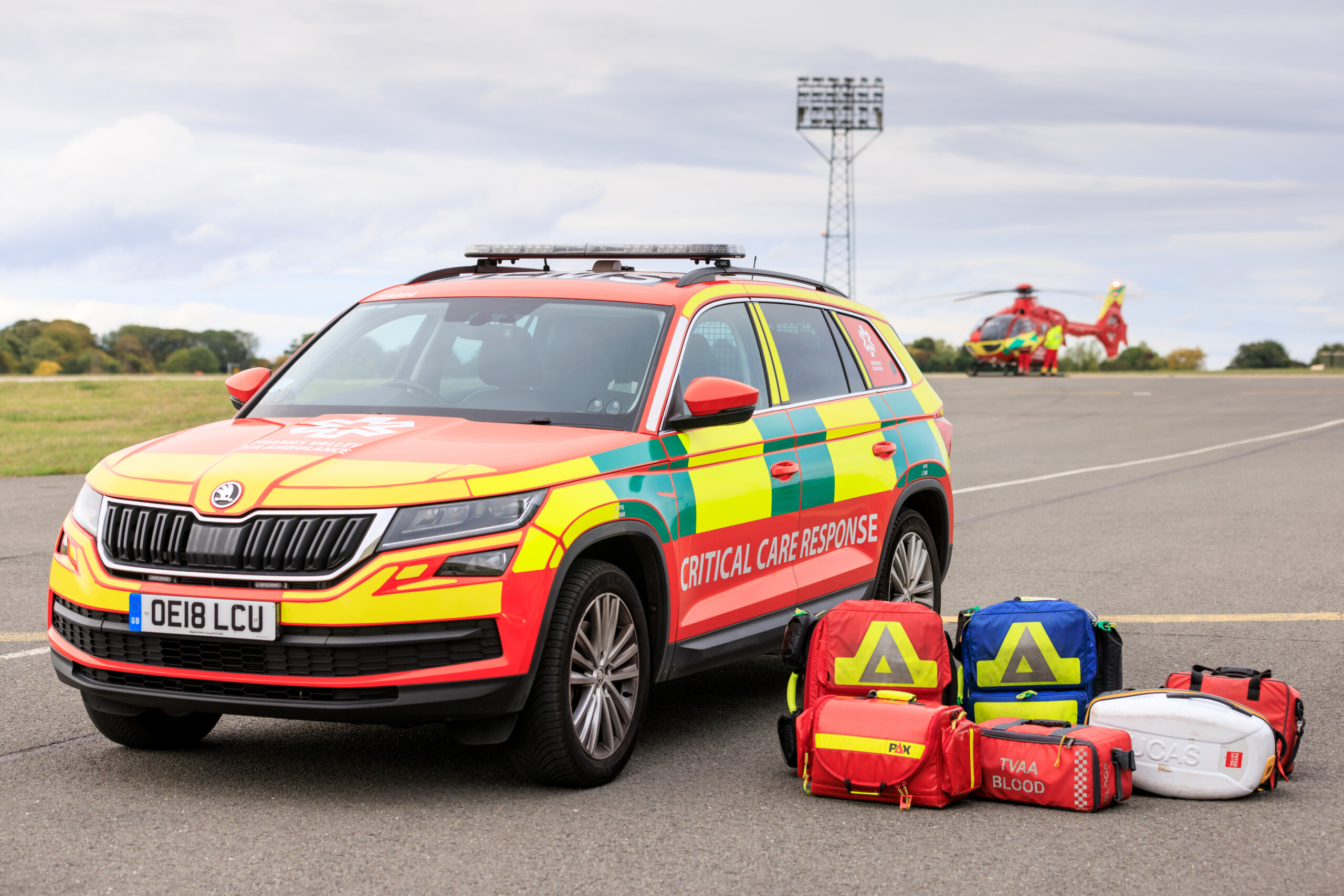 Critical care response vehicle, with kit bags including blood in the foreground and helicopter in the background