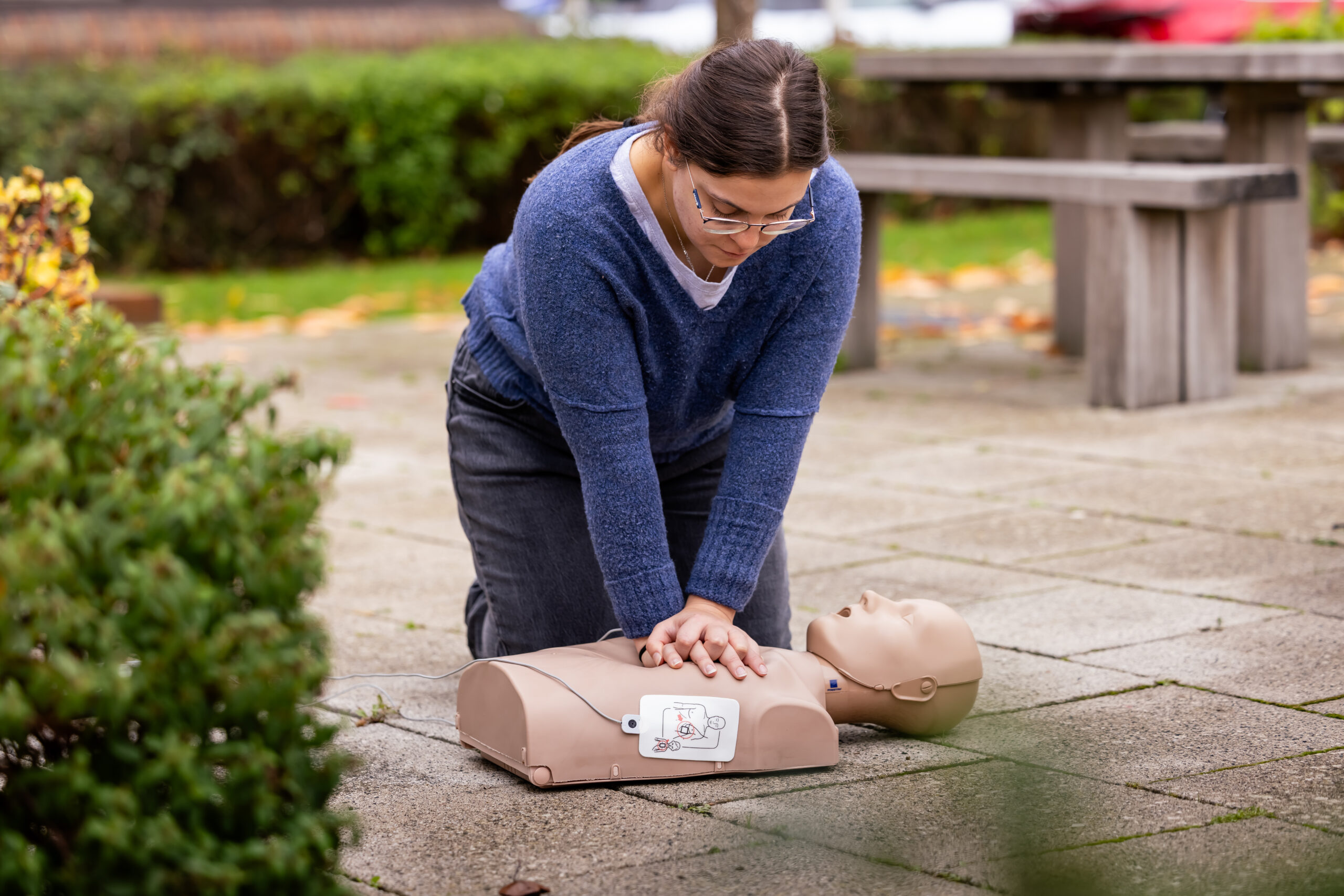 Bystander performing lifesaving CPR on a training manikin