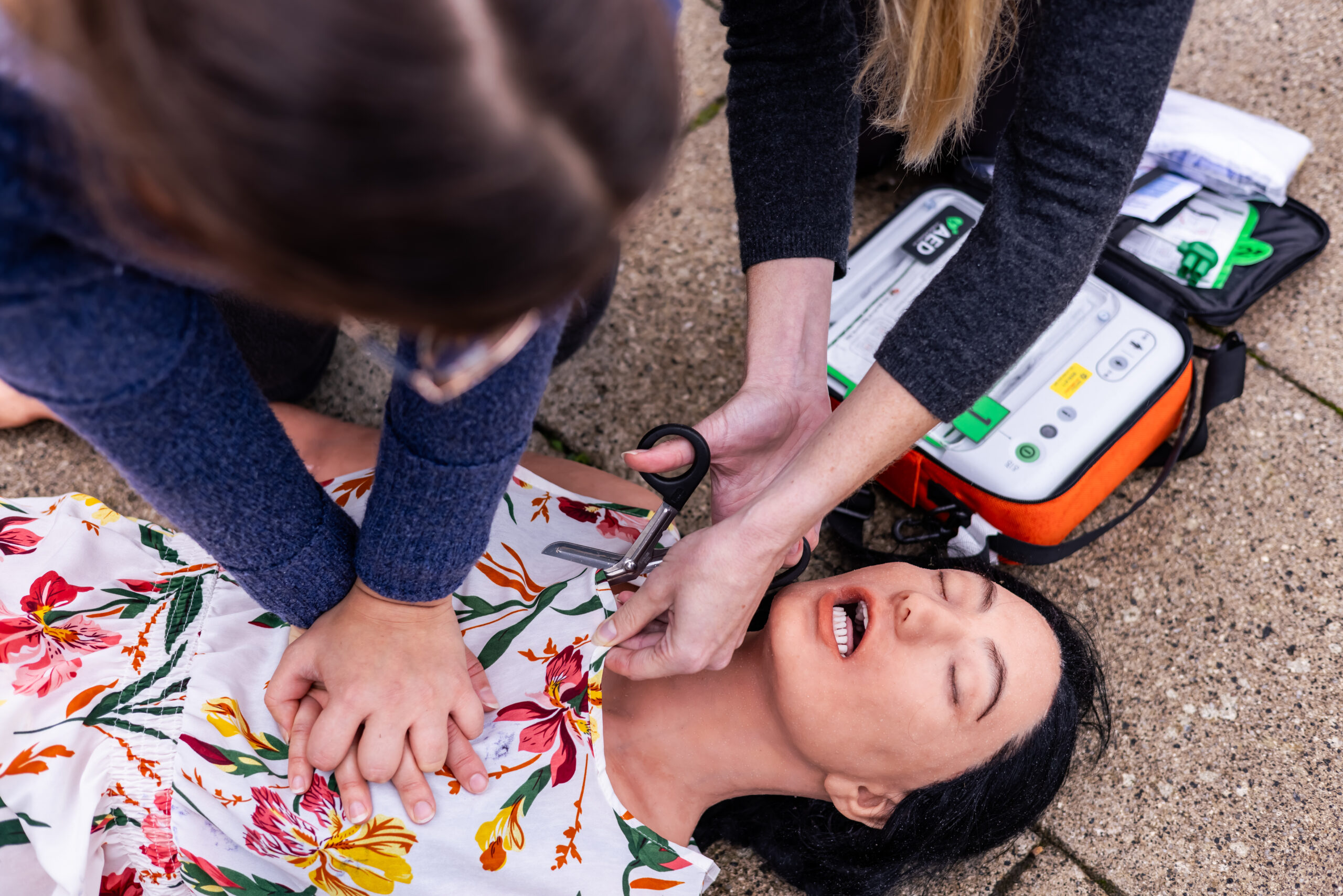 Bystanders expose chest of CPR manikin in order to apply AED defibrillator pads