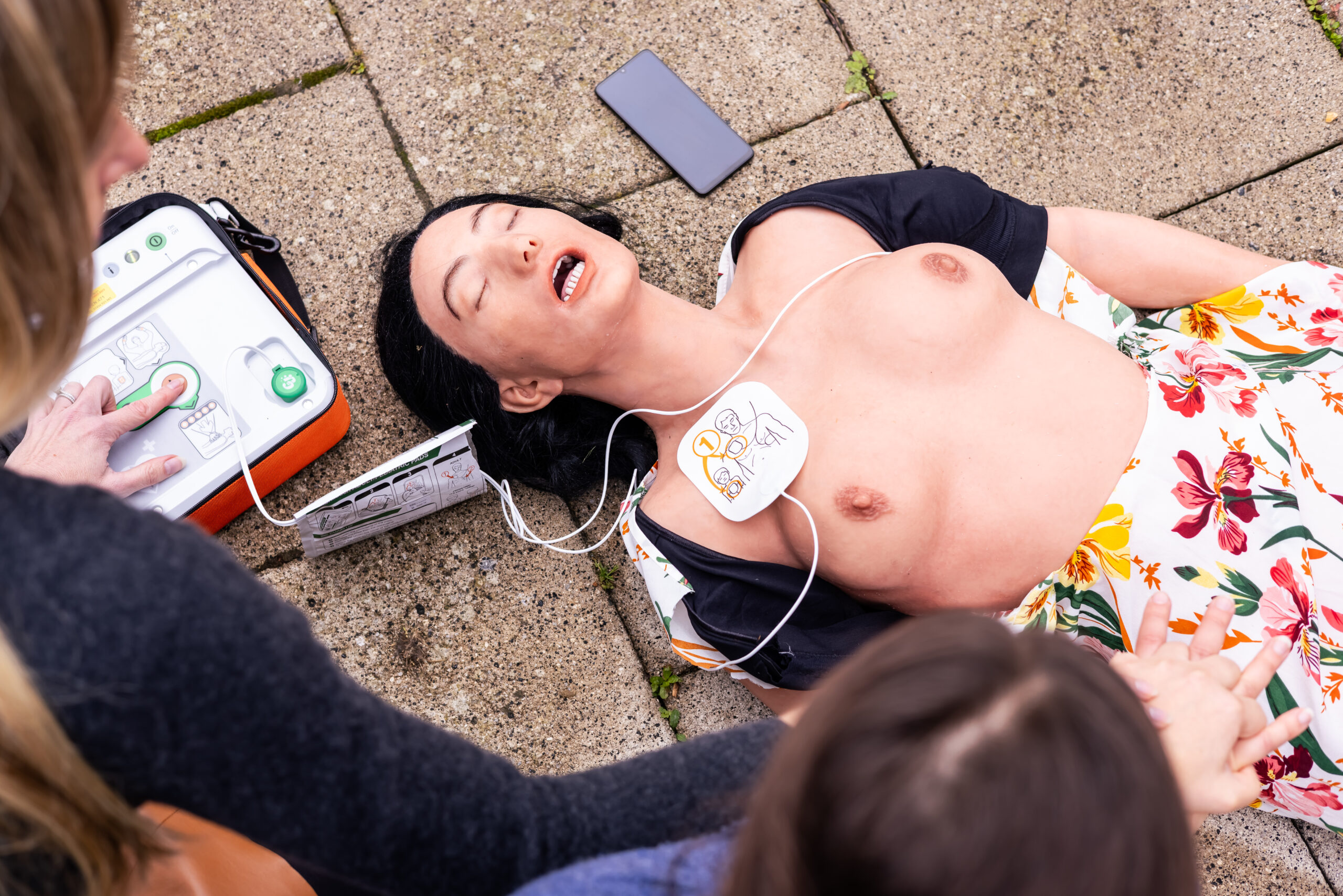 A female CPR manikin showing where defib pads should be placed. 